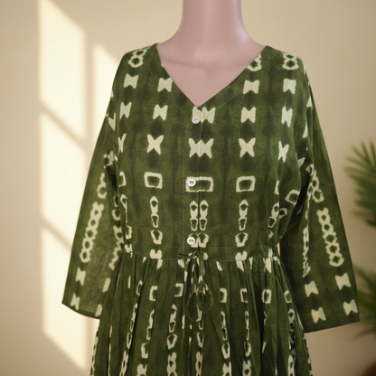 Close-up of olive green geometric print cotton one piece showing V-neckline, button detailing and gathered tie-up waist